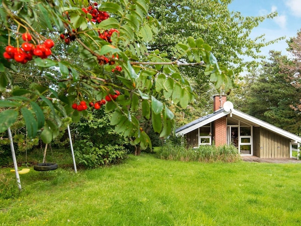 Une maison avec un toit en pente, une façade en briques et un petit porche.