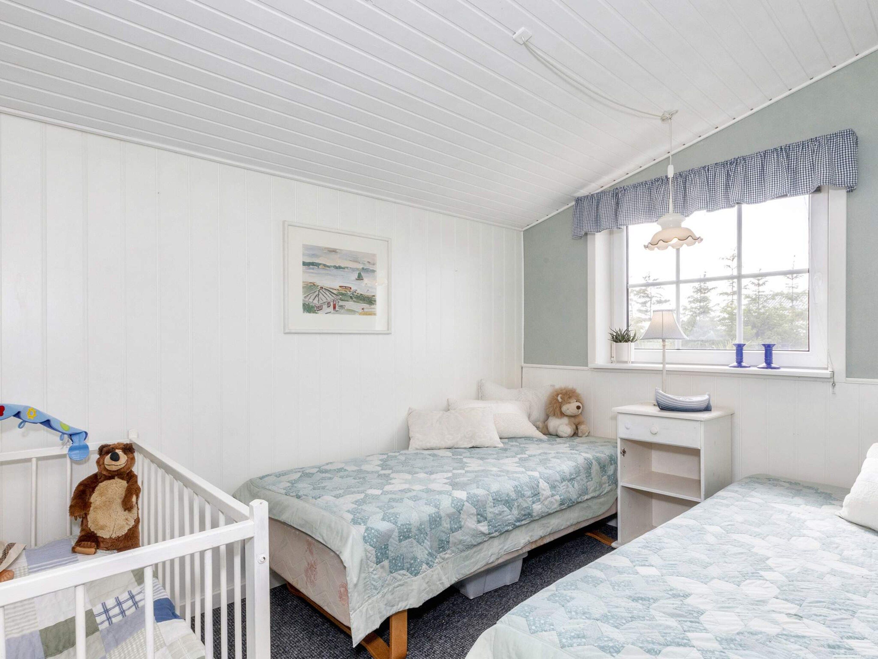 Un dormitorio infantil con dos camas, una cuna, un escritorio y una ventana con cortinas.