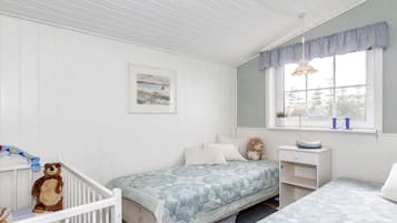 Un dormitorio infantil con dos camas, una cuna, un escritorio y una ventana con cortinas.