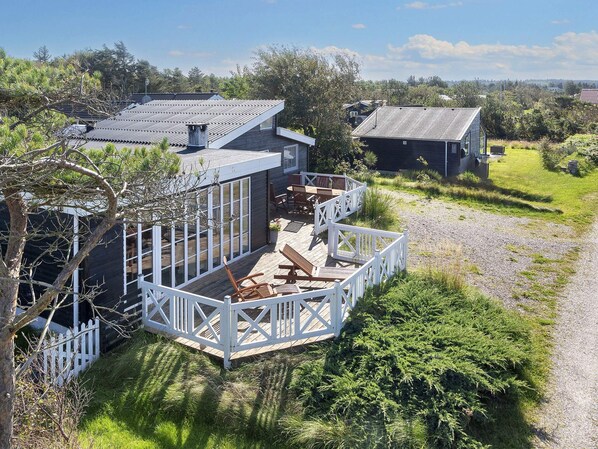 A residential property with a deck, outdoor seating, and a view of the surrounding landscape.