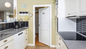 A compact kitchen with white cabinetry, a coffee machine, and a sign indicating a dining area.