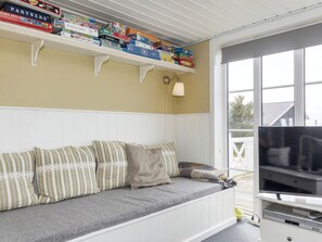 A cozy room with a built-in bench, a television, and a shelf with various board games. - 4 Star Holiday Home in Logstor (Logstor)