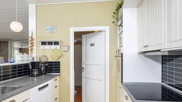 Una cocina compacta con armarios blancos, una máquina de café y un letrero que indica 'Shower Diner' en la habitación contigua.