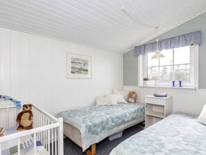 Quarto de criança com duas camas, berço, escrivaninha e janela com vista.