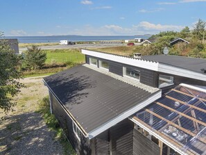 A modern house with a large roof and a view of the sea.