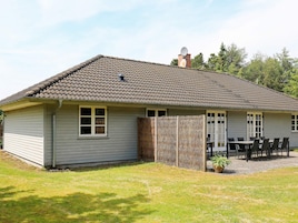 A single-story house with a tiled roof, a fenced patio area, and a satellite dish.