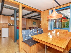 A compact kitchen with a refrigerator, wooden cabinets, and a dining area with a bench and table.