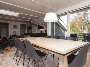 A modern dining area with a large wooden table, black chairs, and a hanging light fixture. - 6 Person Holiday Home in Ebeltoft (Ebeltoft)