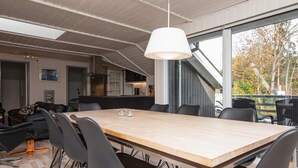 A modern dining area with a large wooden table, black chairs, and a hanging light fixture. - 6 Person Holiday Home in Ebeltoft (Ebeltoft)