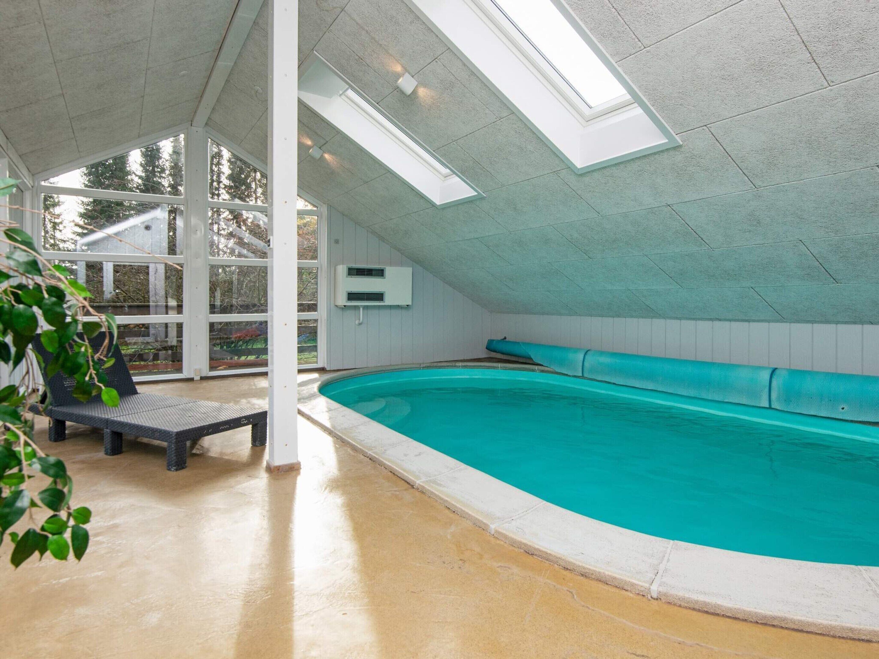 Une piscine dotée d’un plafond incliné et de lucarnes, d’un banc et d’un climatiseur fixé au mur.