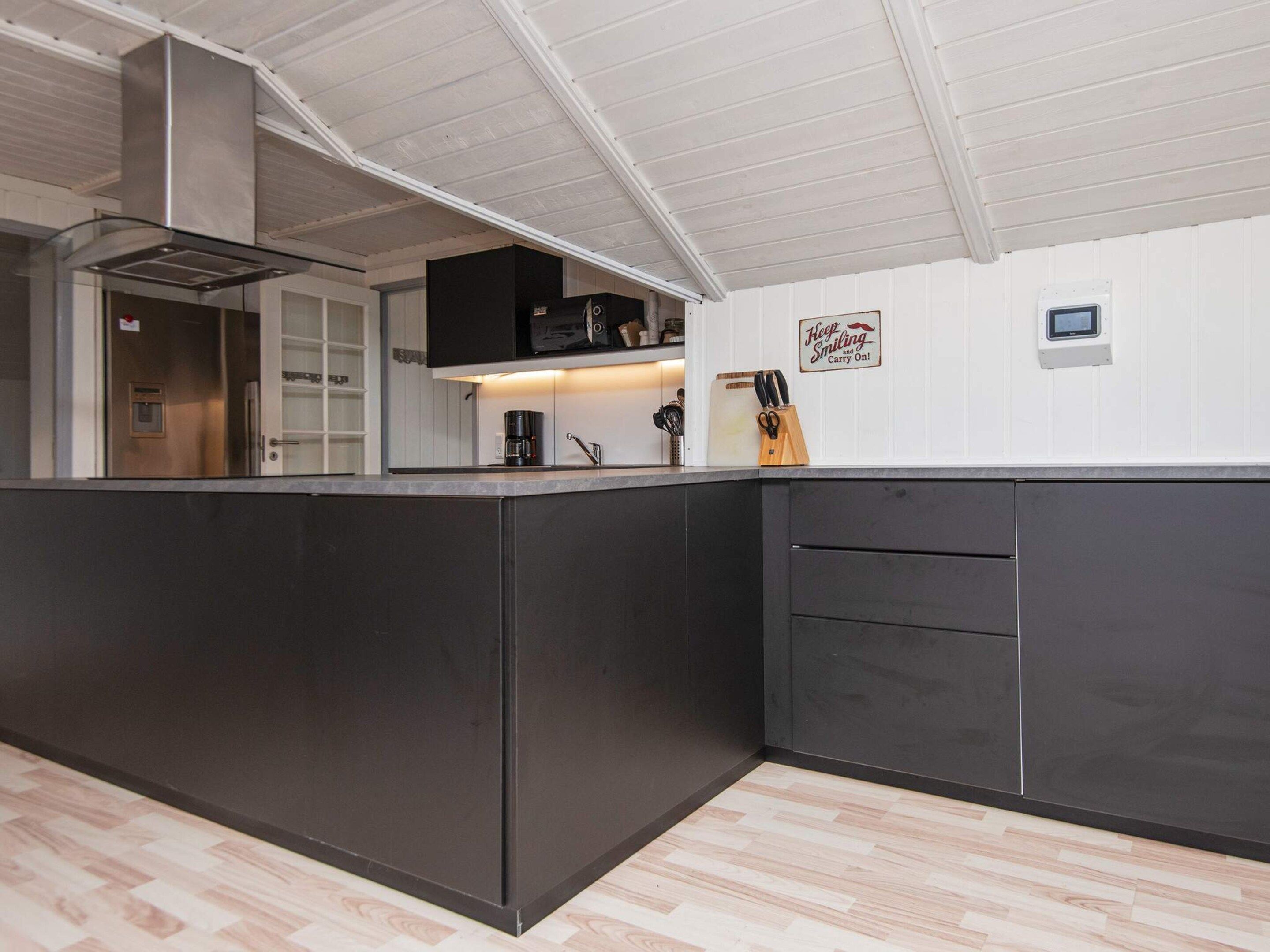 A modern kitchen with a central island, built-in appliances, and a white ceiling.