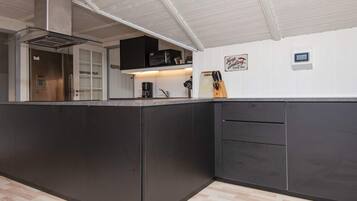 A modern kitchen with a central island, built-in appliances, and a white ceiling.