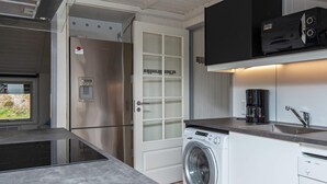 A compact kitchen with a washing machine, a coffee maker, and a microwave. - 6 Person Holiday Home in Ebeltoft (Ebeltoft)