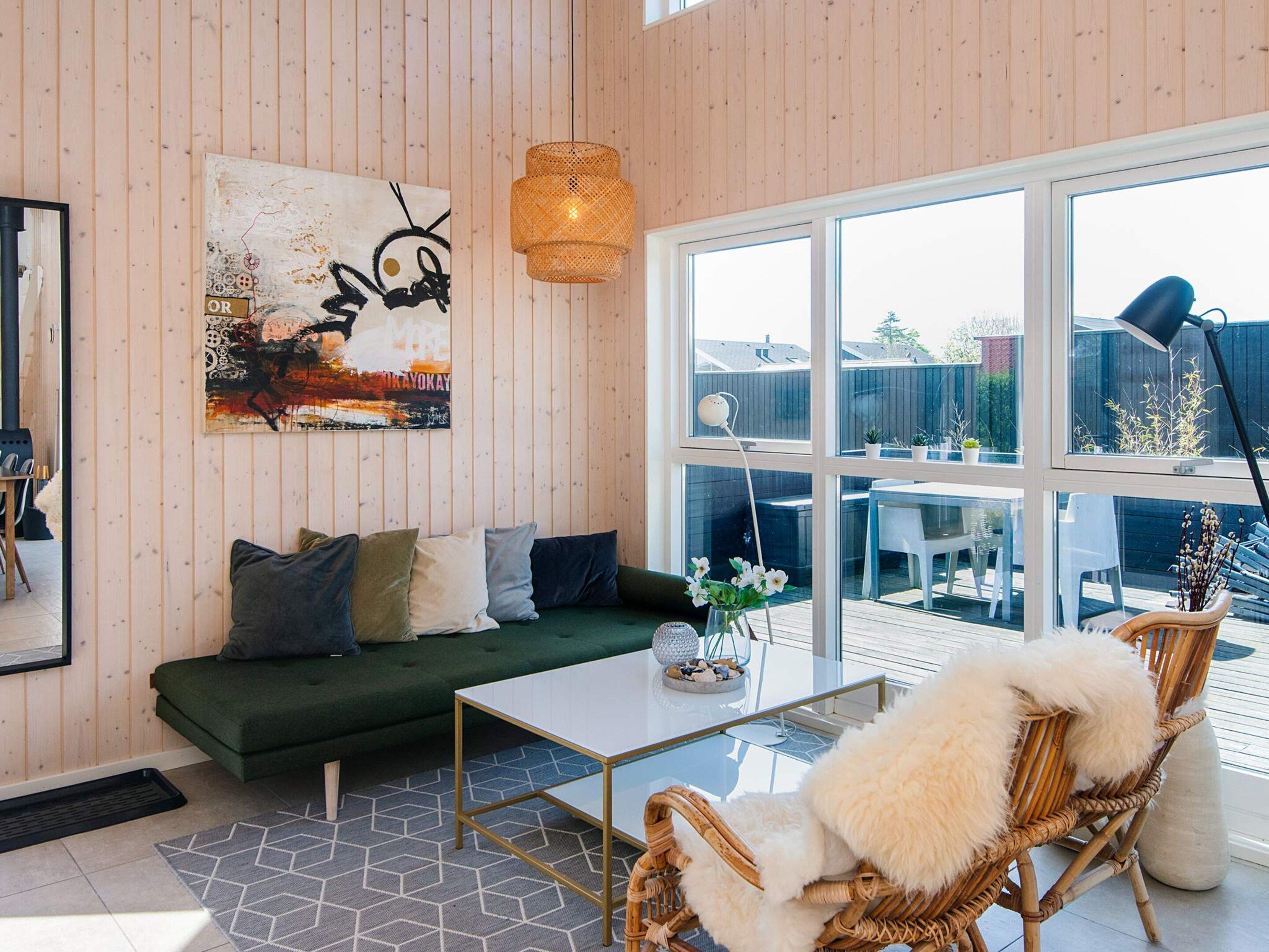 A modern living room with a green sofa, a white coffee table, and wicker chairs.