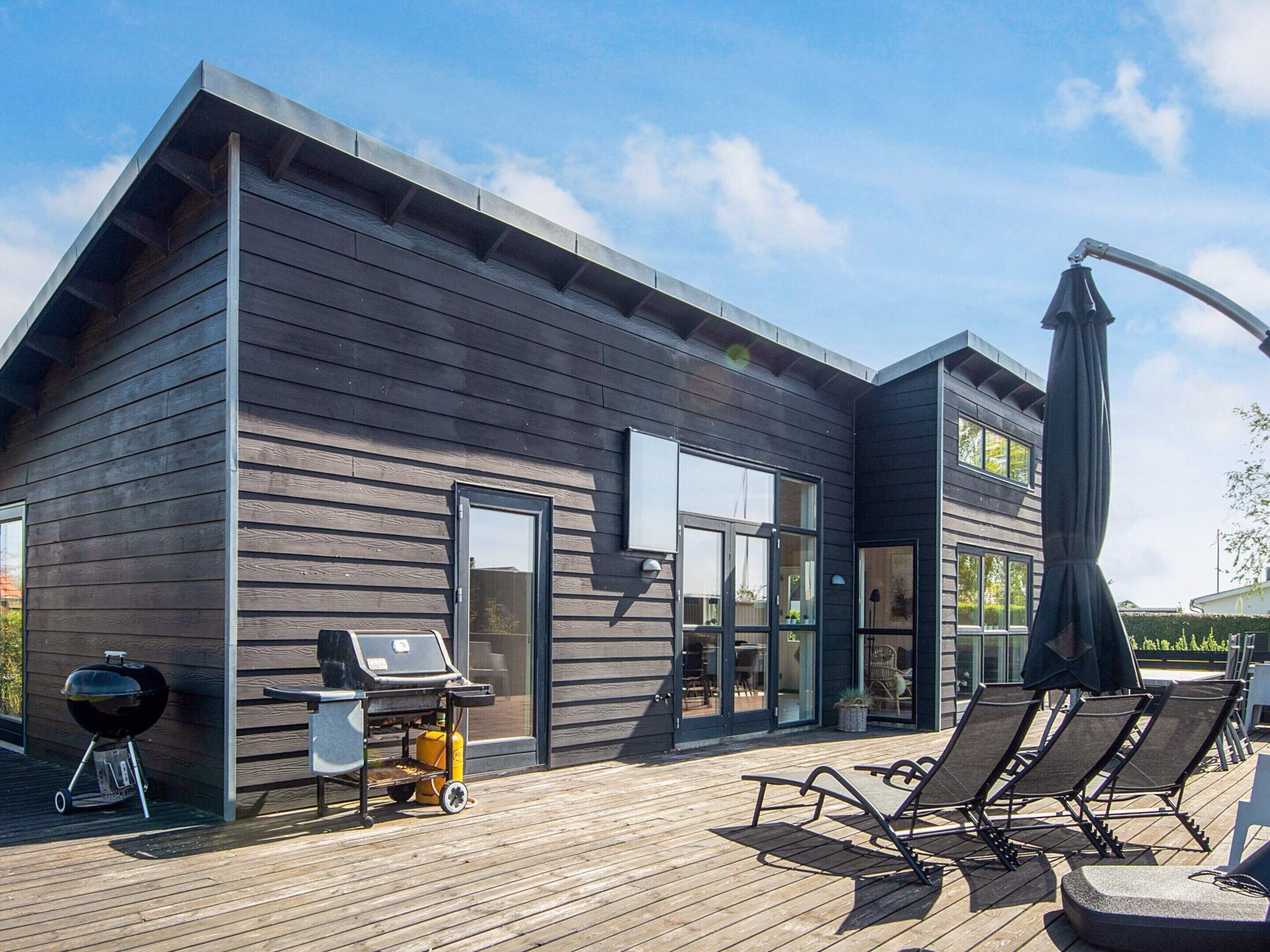 Une maison moderne dotée d’une terrasse, d’un barbecue et d’un espace salon extérieur.