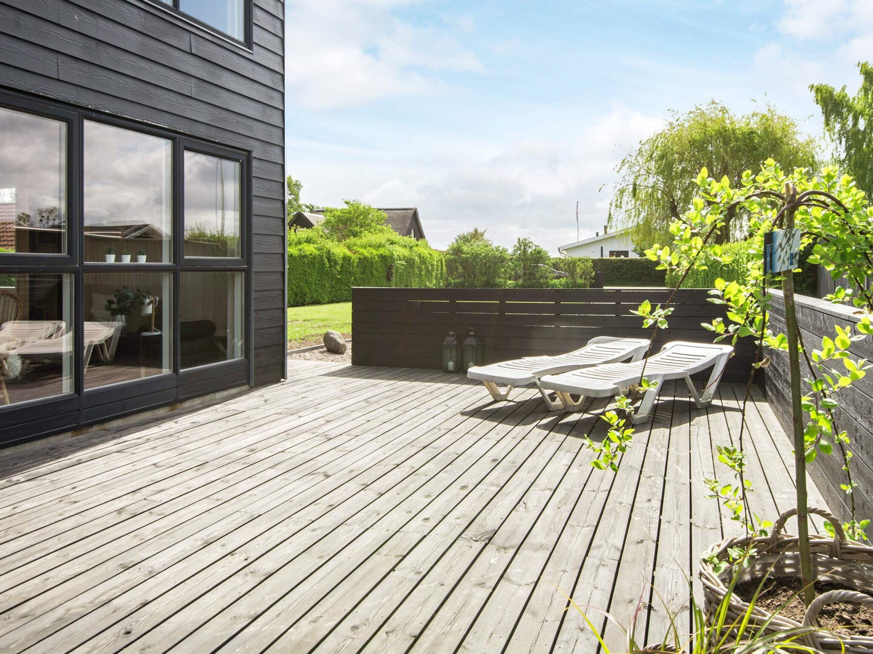 Une terrasse en bois avec des chaises longues et un pot de fleurs.