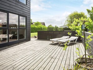 Una terraza de madera con sillones de descanso y una planta en maceta.