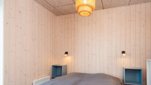 A bedroom with a bed, two bedside tables, and a hanging light fixture. - 4 Star Holiday Home in Bjert (Bjert)