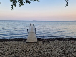 A wooden pier extending into calm waters with a sandy beach and distant land visible. - 4 Star Holiday Home in Bjert (Bjert)