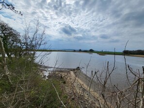 Um rio com margem arenosa e vegetação escassa.
