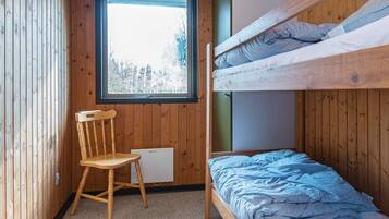 A bunk bed room with a window, a wooden chair, and a desk.