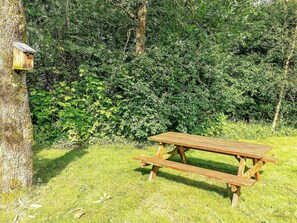 A wooden picnic table in a grassy area with dense foliage in the background. - 6 Person Holiday Home in Toftlund (Toftlund)
