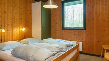 A wooden-paneled room with a bed, a window, and a hanging light fixture.