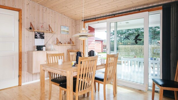 A wooden-paneled room with a dining table, chairs, a coffee maker, and a large window with a view of greenery. - 6 Person Holiday Home in Tarm-by Traum (Tarm)