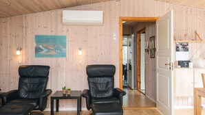 A room with two leather chairs, a small table, an air conditioning unit, and a painting on the wall. - 6 Person Holiday Home in Tarm-by Traum (Tarm)