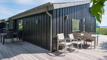 Un espacio de estar moderno al aire libre, con cubierta de madera y sillas de metal.
