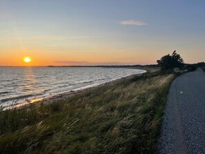 A coastal road with a view of the ocean and a sunset.
