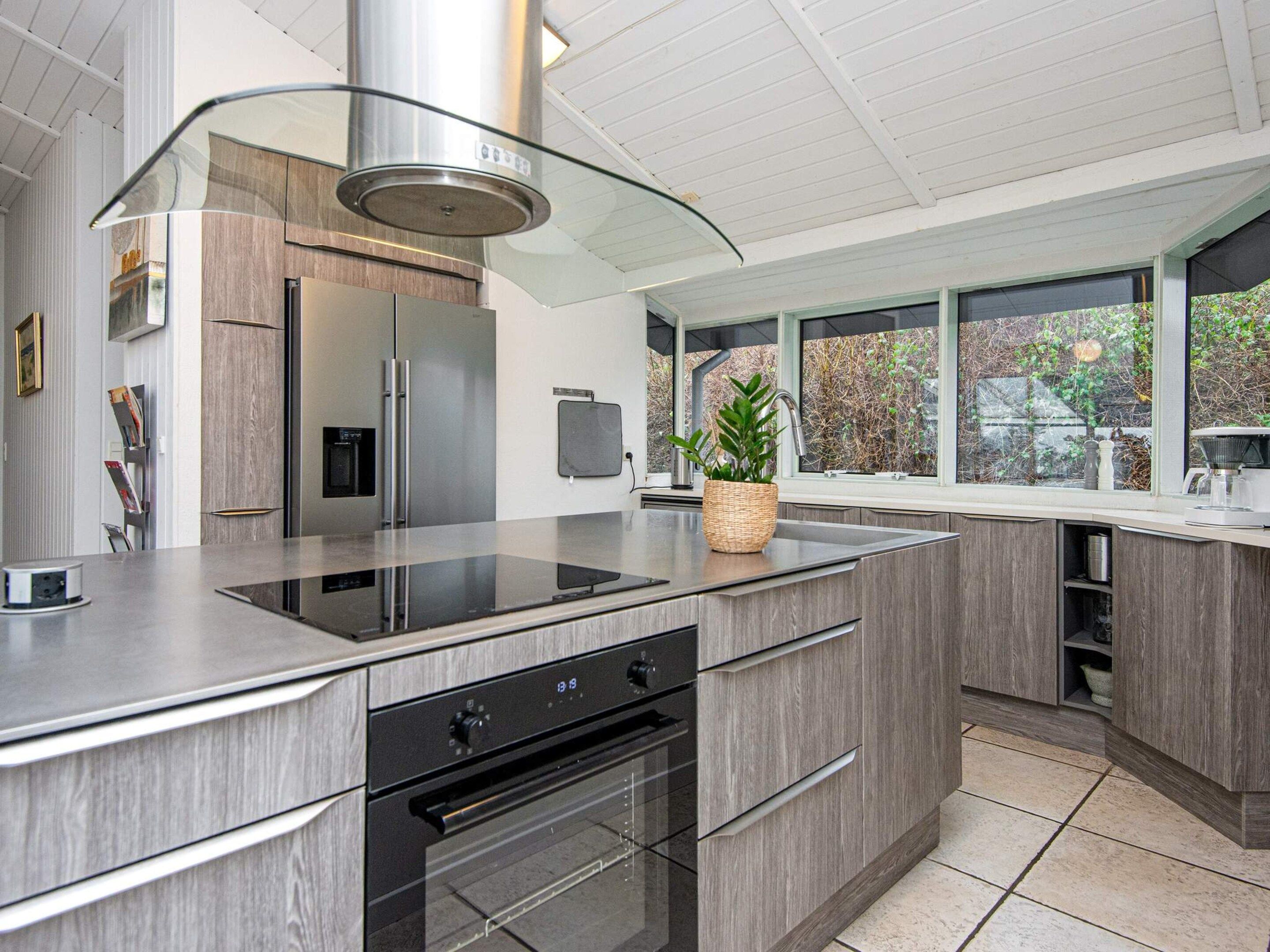 Una cocina moderna con una campana de acero inoxidable, horno empotrado y un amplio ventanal con vistas al exterior.