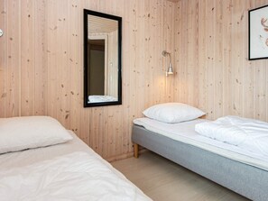 Quarto com duas camas, um espelho, uma luminária na parede e um quadro emoldurado.