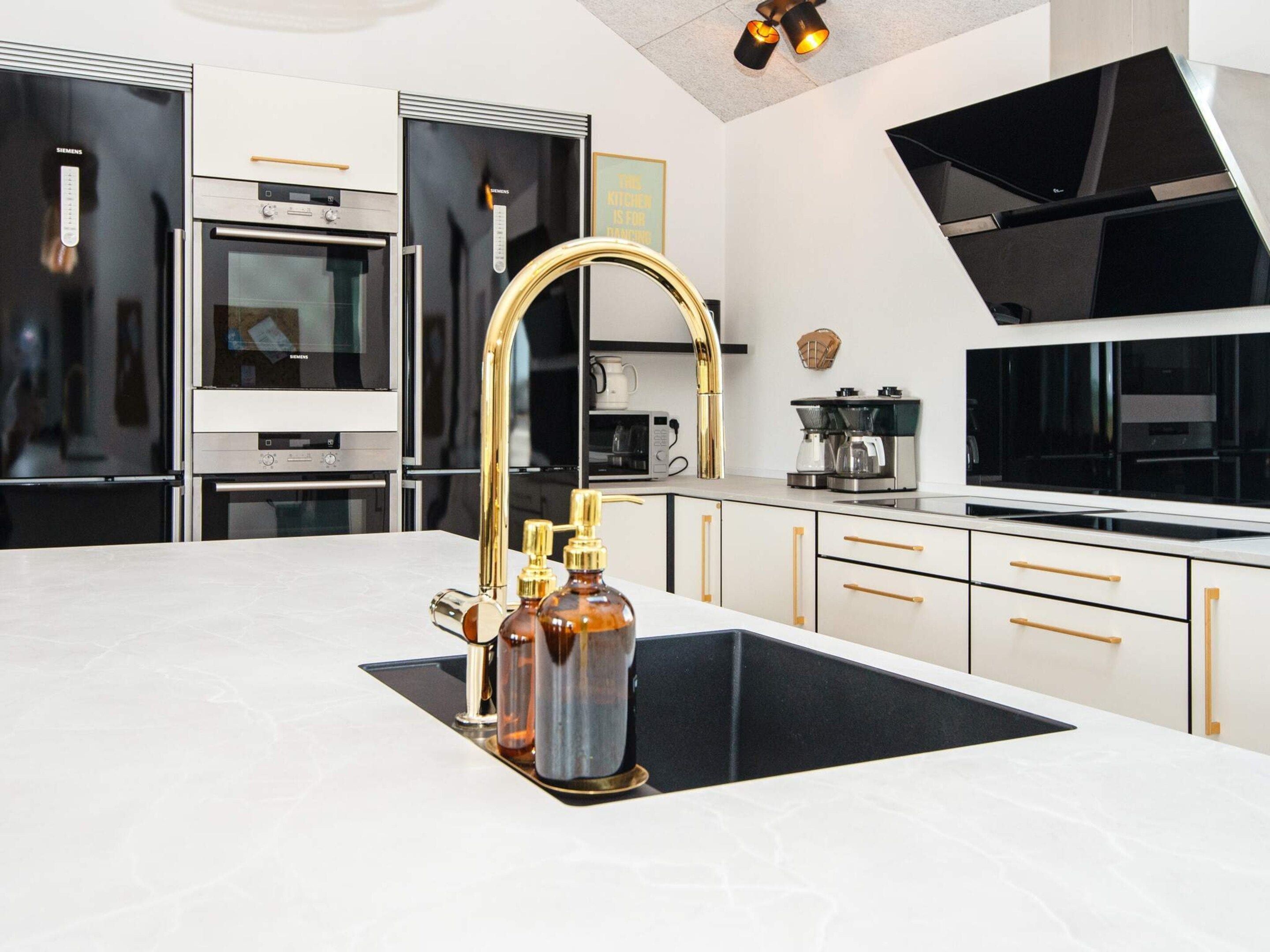 Una cocina moderna con una isla central, electrodomésticos de acero inoxidable y un grifo dorado.