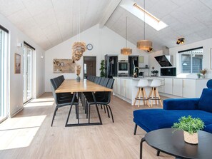 A modern kitchen with white cabinets, a black stove, and a large island with bar stools. - 5 Star Holiday Home in Harboore (Harboore)