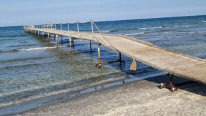 Une jetée en bois s’étendant dans l’océan, avec une eau claire et une mer calme.