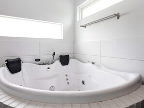 A modern bathroom with a freestanding bathtub, a handheld showerhead, and a towel rack.