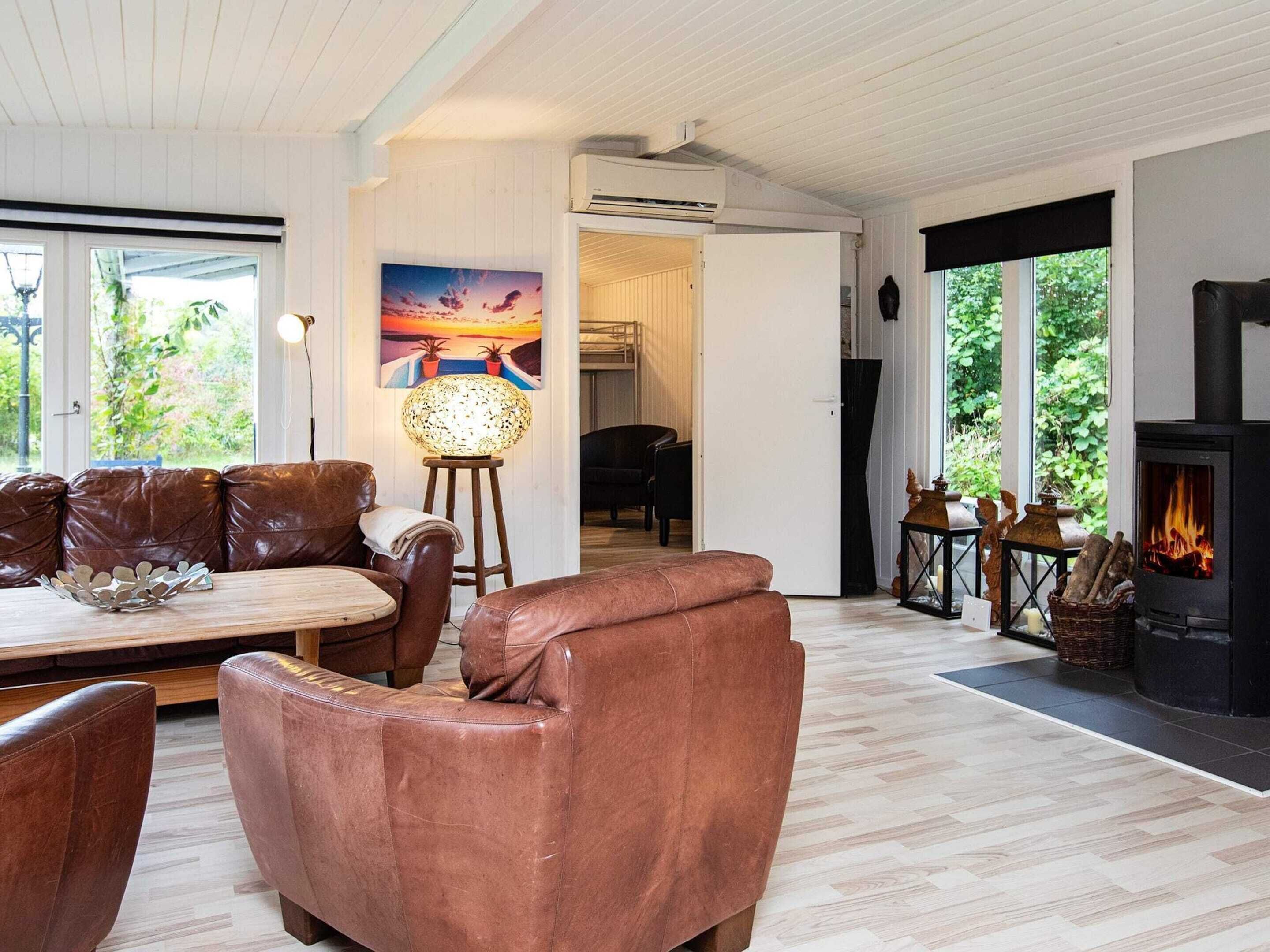 A modern living room with leather furniture, a fireplace, and large windows offering a view of the outdoors.