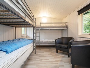 A bunk bed room with a single bed on the left, a chair, and a window with a view of greenery. - Secluded Holiday Home in Lolland near Sea (Dannemare)