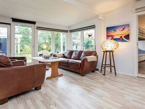 A cozy living room with a brown leather sofa, a wooden coffee table, and a standing lamp. - Secluded Holiday Home in Lolland near Sea (Dannemare)