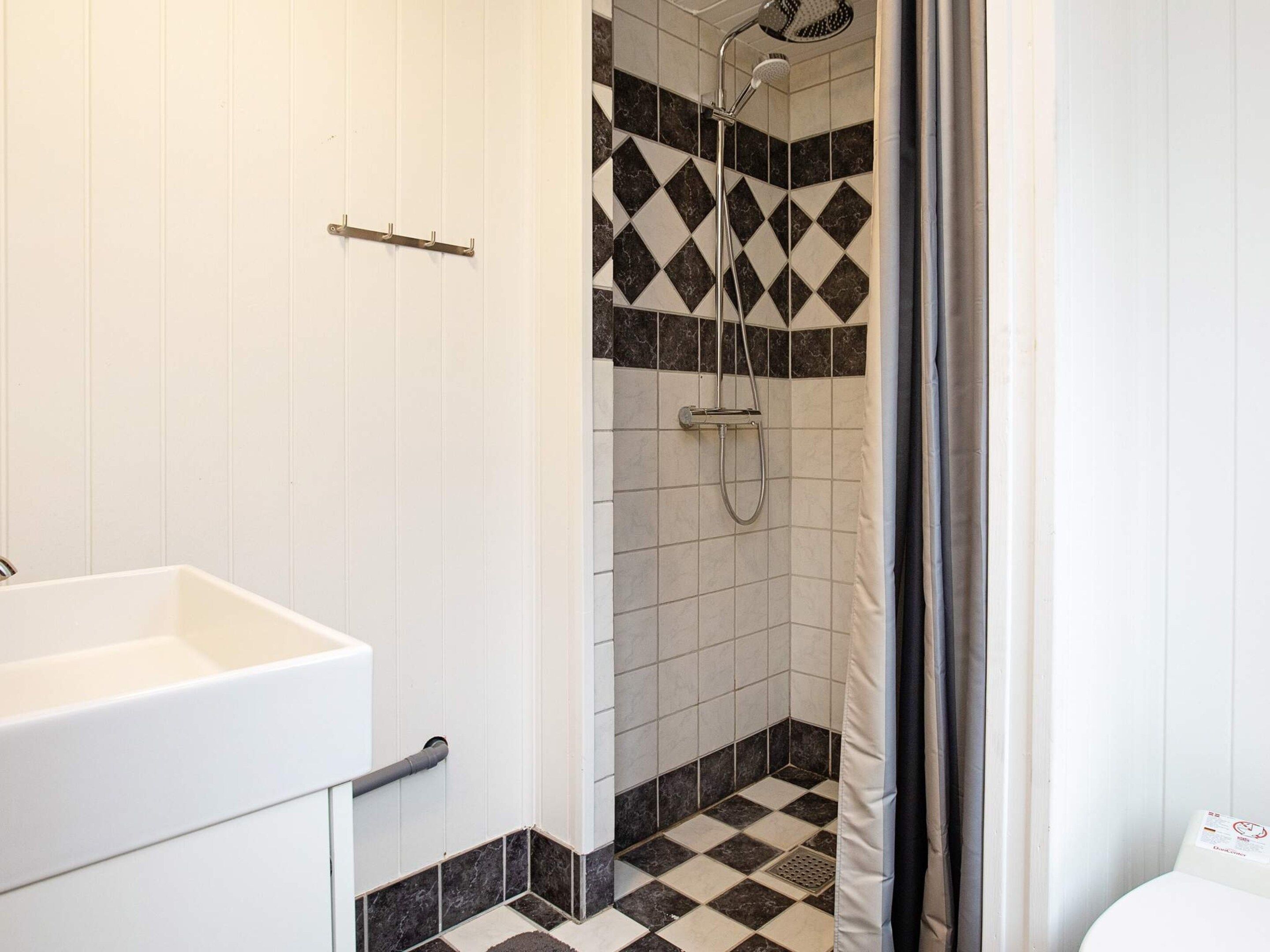 A bathroom with a shower, a sink, and tiled flooring.