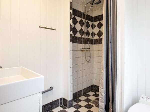 A bathroom with a shower, a sink, and tiled flooring. - Secluded Holiday Home in Lolland near Sea (Dannemare)