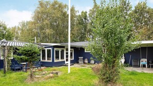 Ein blaues Haus mit überdachter Veranda, einem kleinen Garten und Sitzgelegenheiten im Freien.