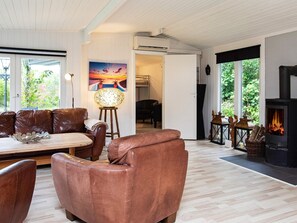 Una sala moderna con sofás de cuero, una mesa de comedor, una chimenea y un cuadro en la pared.