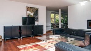 Una sala de estar moderna con un sofá de cuero negro, una mesa de centro de vidrio y un mueble de entretenimiento negro con un televisor de pantalla plana.