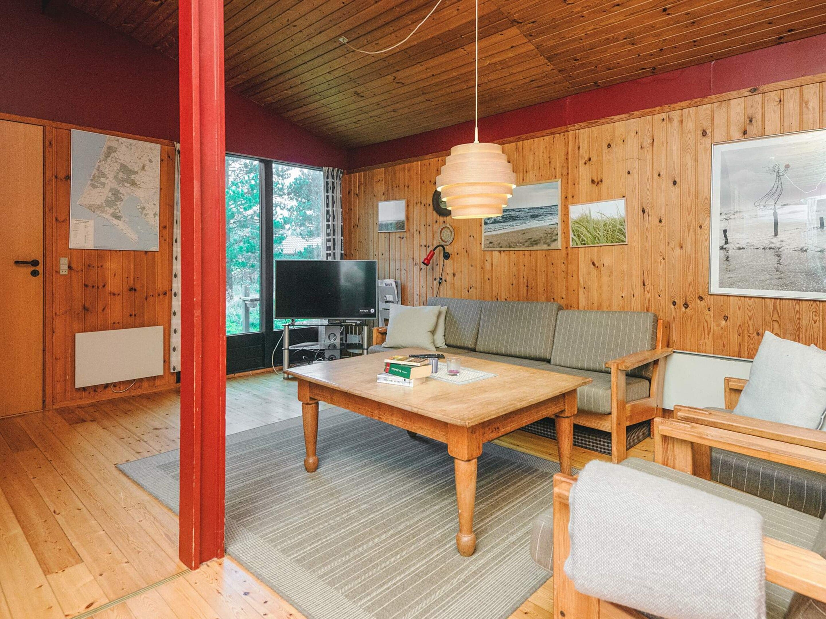 A cozy room with a wooden floor, a sofa, a table, and a television.