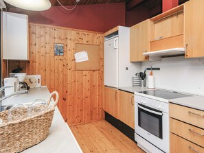 A kitchen with wooden cabinets, a Bosch oven, a white refrigerator, and a corkboard with a note. - Charming Holiday Home in BlÃ¥vand with Hot Tub (Blavand)