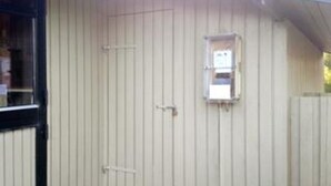 Un edificio con facciata beige, una piccola finestra e una porta.