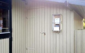 A building with a beige exterior, a small window, and a door. - Charming Holiday Home in BlÃ¥vand with Hot Tub (Blavand)