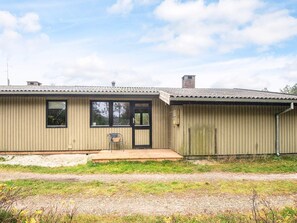 A single-story building with a flat roof, a front door, and a small porch. - Charming Holiday Home in BlÃ¥vand with Hot Tub (Blavand)